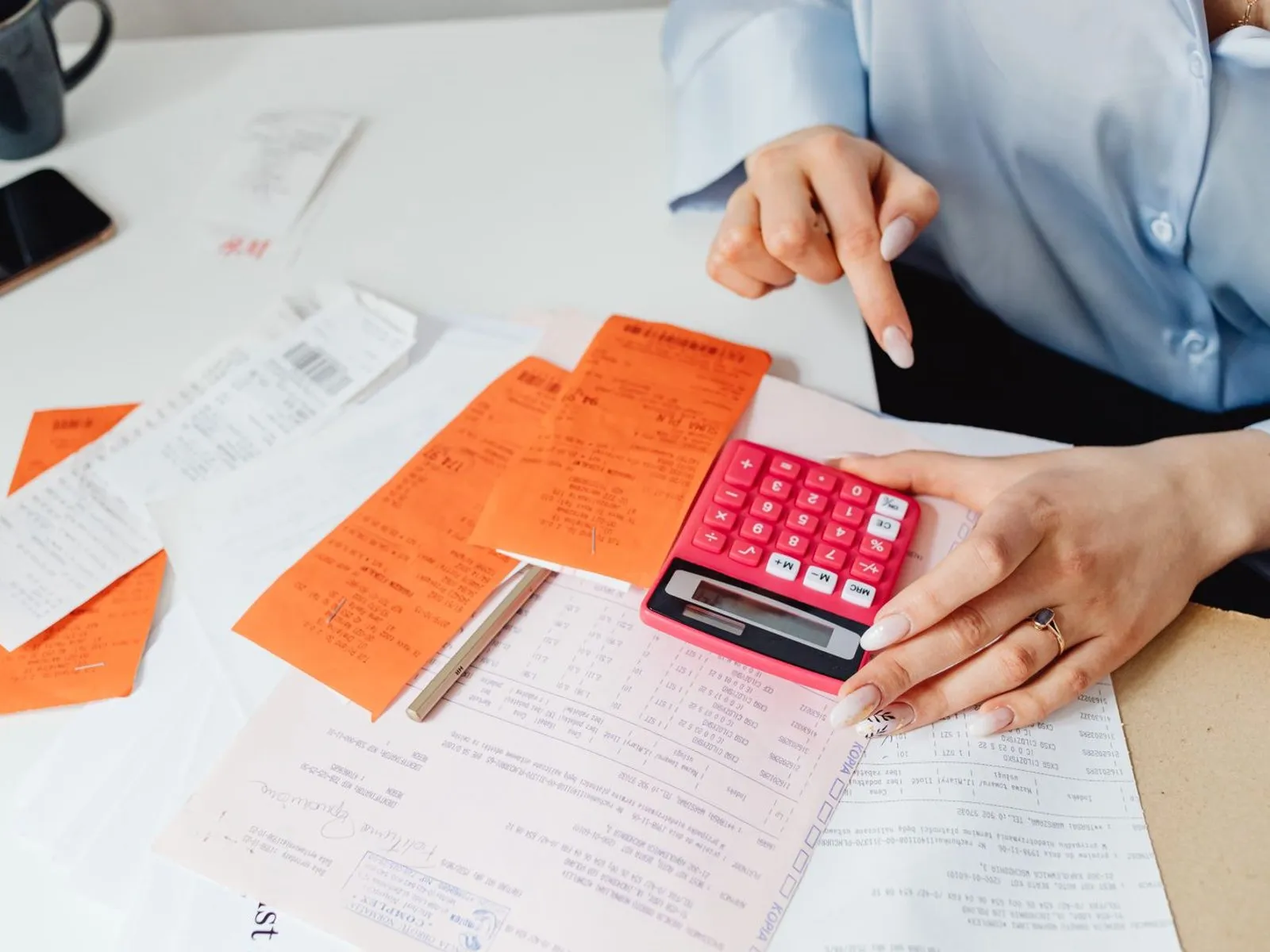 Chef d'entreprise analysant un tableau de coût de revient avec calculatrice et documents financiers